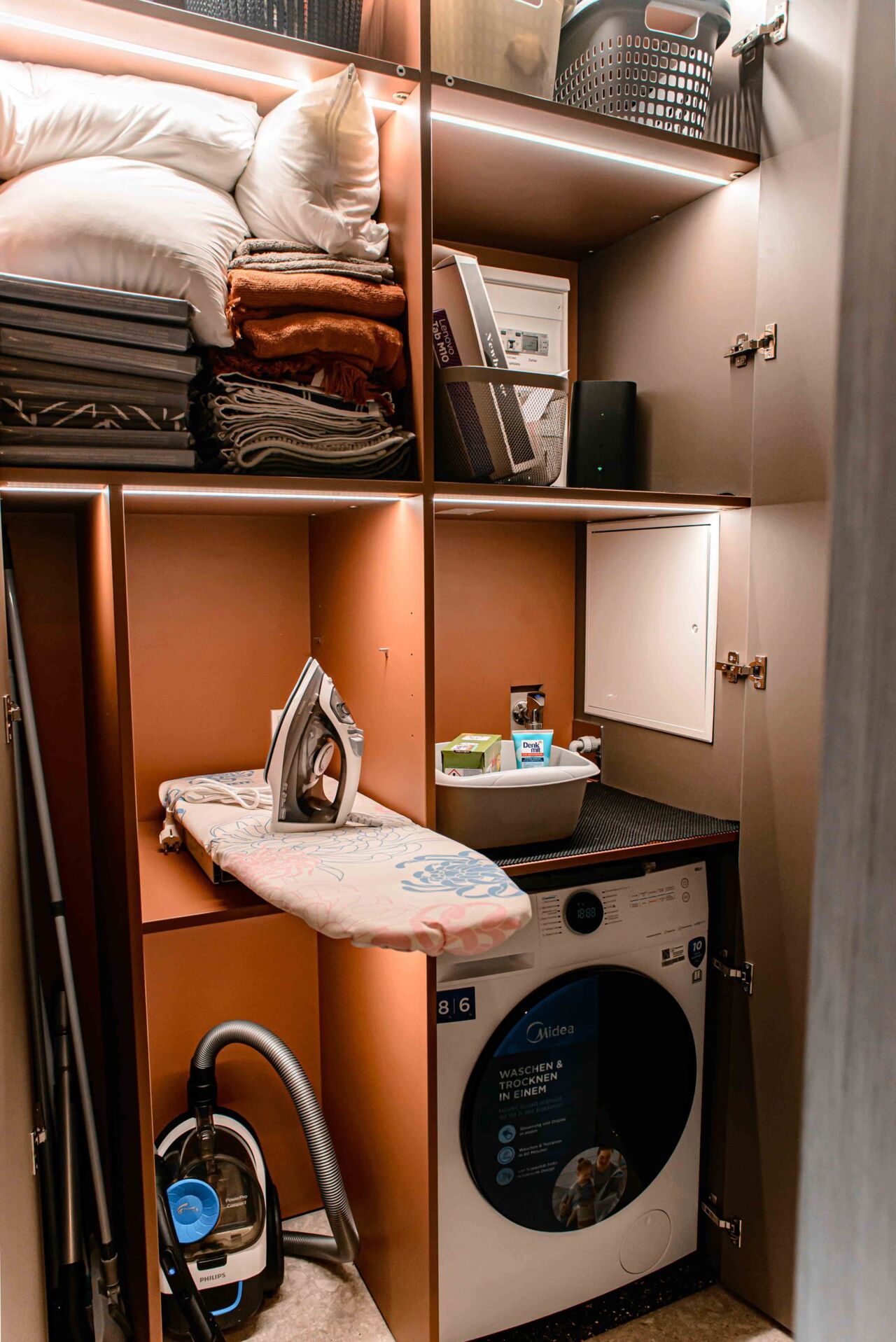 geöffnete Schränke mit Waschmaschine in Ferienwohnung
